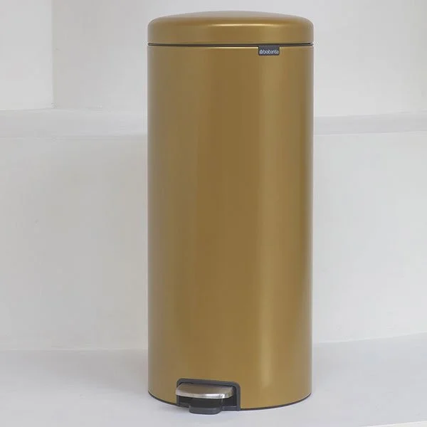 a gold trash can on a white surface